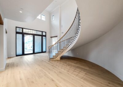 Custom curved free standing wood staircase with wrought iron railing in luxury Title home