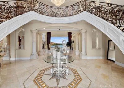 Grand curved symetrical freestanding staircase with custom wrought iron railing, marble floors, and chandelier in luxury home interior
