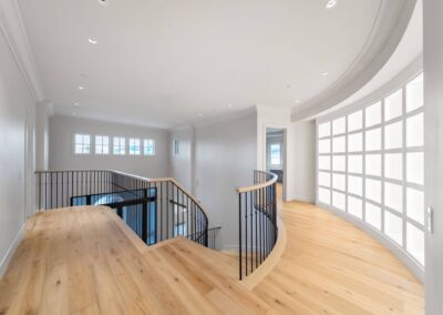 Custom curved free standing wood staircase with wrought iron railing in luxury home